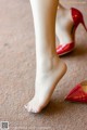 A close up of a woman's feet wearing red high heels.