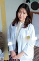 A woman in a white lab coat sitting on a bed.