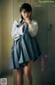 A woman in a school uniform standing in front of lockers.