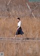 A woman walking across a wooden bridge in a field.