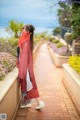 A woman wearing a red scarf standing on a brick walkway.