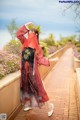 A woman in a red and black kimono standing on a brick walkway.