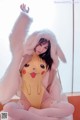 A woman in a pikachu costume sitting on a bed.